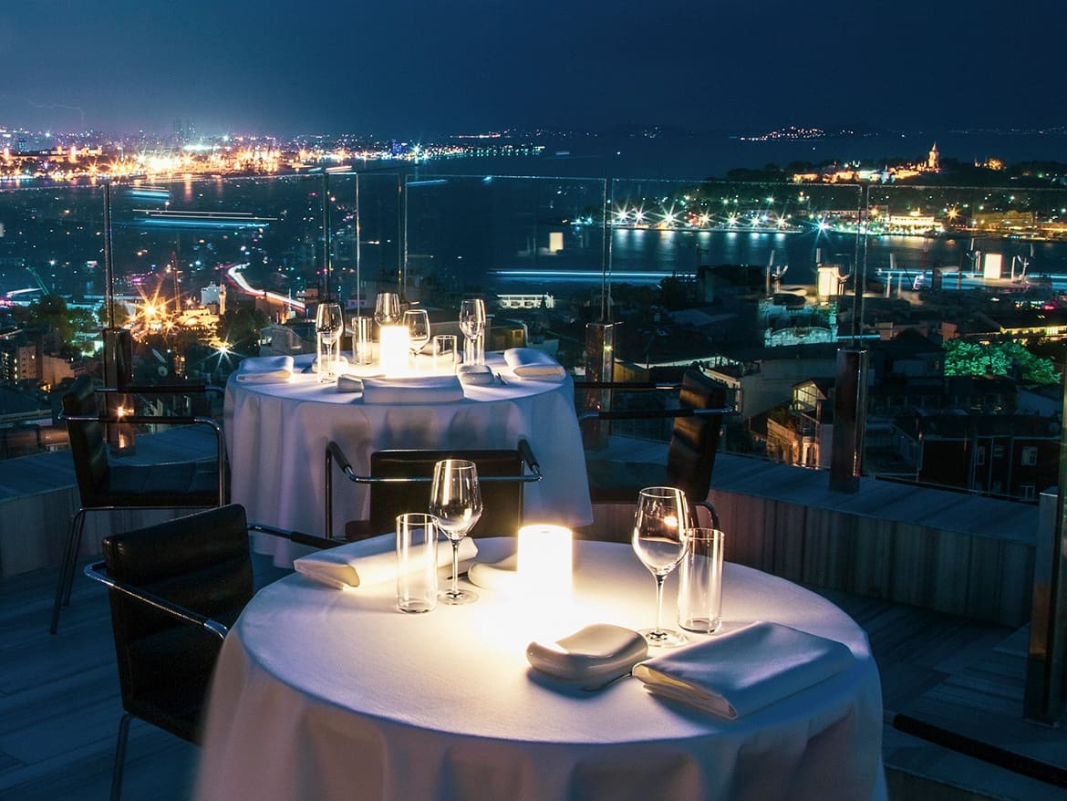 Una mesa de cena en una azotea sobre el Bósforo, de noche